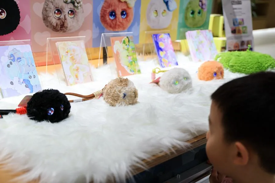 一名儿童在深圳全球创新旗舰店内与AI玩具“芙崽Fuzozo”互动